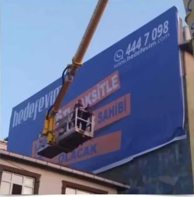 Sepetli araçla bina cephesine baskılı vinil branda gerilirken