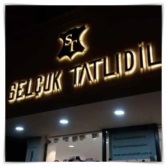 Gece arkadan ışıklı altın renk harfler ve logo, mağaza cephesi