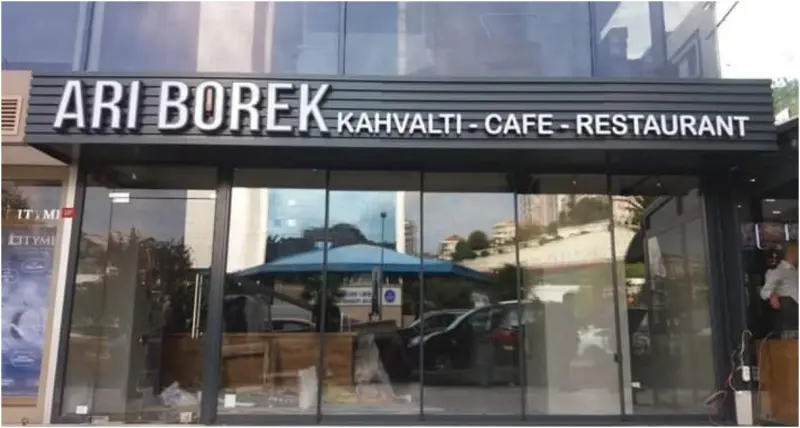 Lamel kaplı cephe paneli üzerinde beyaz pleksi kutu harfler, kafe restoran girişi
