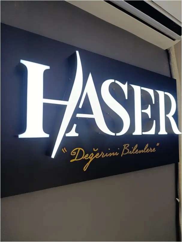 Siyah panel üzerinde önden ışıklı beyaz pleksi kutu harf, gece görünümü