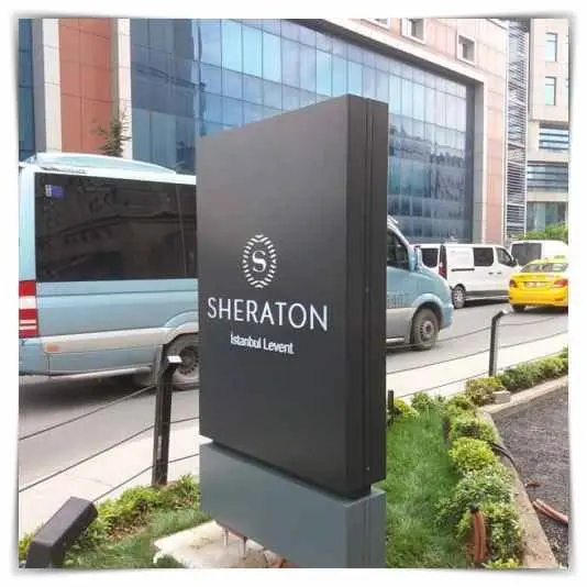 Otel girişinde beton kaide üzerinde siyah totem tabela