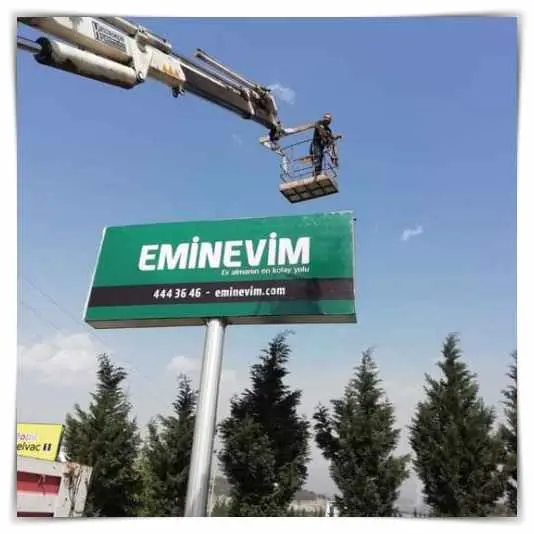 Yol kenarında direkli yeşil pilon tabela, sepetli araçla montaj